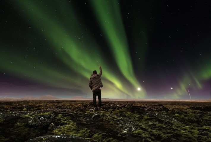 Man standing under the Northern Lights in Iceland
