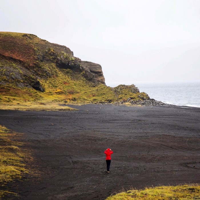 Woman walking over black sand beach